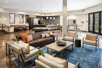 A spacious living room with a variety of seating options and a kitchen area in the background.